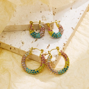 Detail of gold-plated rainbow hoop earrings with colorful crystals on travertine stones