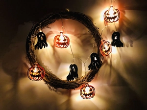 Detail of LED Halloween string lights with glowing pumpkins and ghosts on a rattan wreath