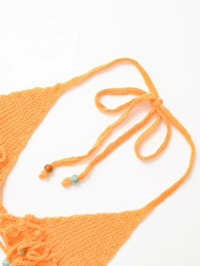 Detailed macro view of orange knit swimwear featuring decorative beads and woven straps