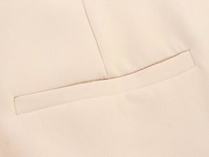 Detail of welt pocket craftsmanship on beige commute suit with fine woven fabric texture