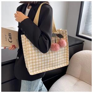 Detail of canvas tote bag in houndstooth pattern with pink cherry charm accessory