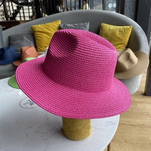 Detailed texture of rose pink straw sun hat with classic fedora top and wide brim