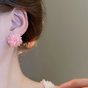 Nahaufnahme von rosa Perlen-Ohrsteckern in Blumenform, die von einem Model getragen werden
