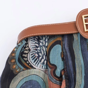 Detail eines farbenfrohen Midi-Rocks mit Goldfaden-Print und braunem Ledergürtel