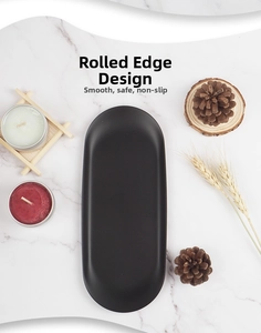 Close-up of matte black oval metal tray featuring a safe rolled edge design on marble