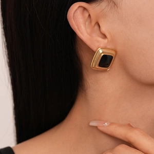 Close-up of vintage gold and black square geometric earrings on a female model
