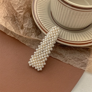 Close-up of rectangle pearl hair clip on brown leather and vintage ceramic textures