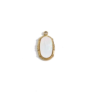 Close-up of golden oval pendant featuring white mother of pearl and bamboo texture