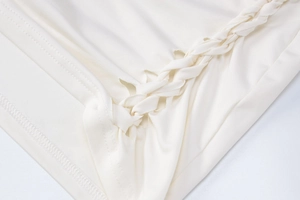Détail du tissu tricoté blanc avec d'élégants éléments décoratifs tressés