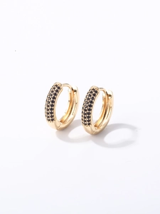 Détail macro de boucles d'oreilles créoles dorées serties de zircons noirs et fermoir