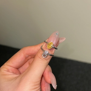 Detail of two S925 silver rings featuring yellow and white oval cut stones on fingers
