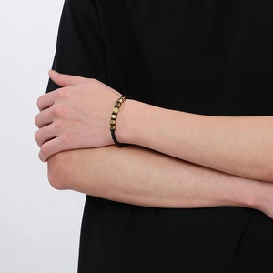 Men's woven black leather bracelet with geometric gold clasp on a model's wrist