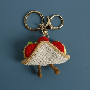 Handmade crochet sandwich keychain with golden lobster clasp on blue background