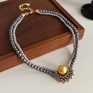 Detailed macro shot of vintage pearl necklace with a golden sunflower pendant and crystals