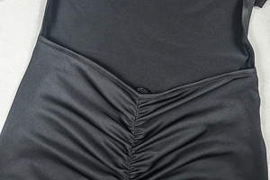 Detailed view of the black ruched texture and V-shaped pleats on the fitted dress fabric
