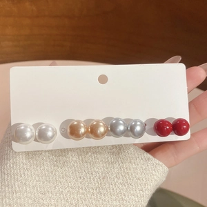 Detail of four pairs of vintage pearl stud earrings in white, champagne, silver and red