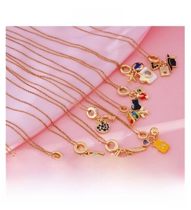 Detailed macro view of 18K gold plated charms with travel motifs on pink silk background