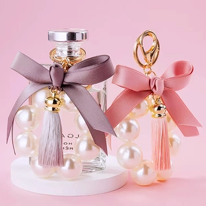 Detail of cute pearl bow tassel keychains in pink and purple for women bags