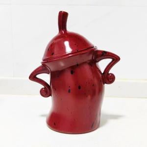 Detail of red ceramic canister with black spots and unique hands-on-hips design