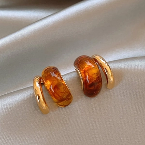 Detailed close-up of retro C-shaped earrings with amber resin and golden metal on silk