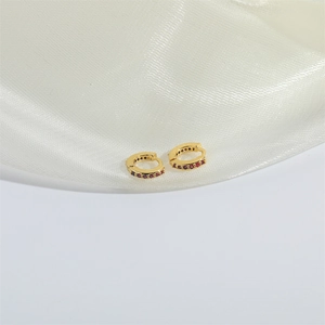 Minimalist gold hoop earrings with small red zircon stones on elegant white silk fabric