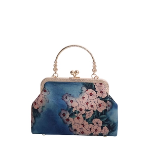 Retro floral handbag with gold metal frame and handle on a white background