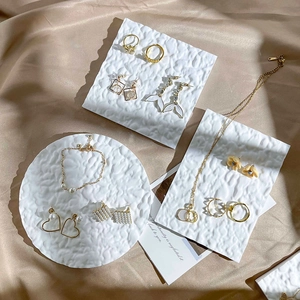 Golden jewelry display set with heart earrings and pearl necklaces on textured trays