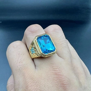 Détail d'une bague hip hop pour homme en or avec pierre bleue et accents de croix en diamant