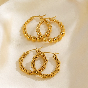 Boucles d'oreilles créoles en acier doré perlé et torsadé sur fond de soie élégant