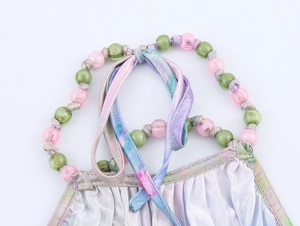 Détail de bretelles perlées et tissu plissé argenté brillant avec des liens tie-dye colorés