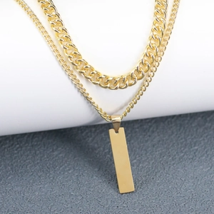 Macro shot of gold double-layered necklace with cuban links and rectangular bar pendant