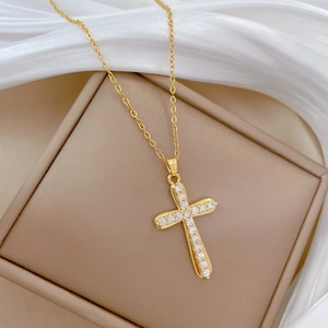 Elegant gold titanium cross pendant necklace with sparkling cubic zirconia on jewelry box