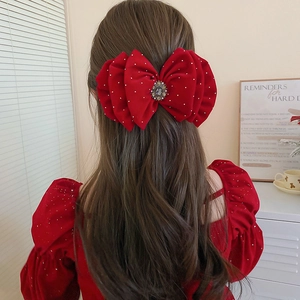 Detail of red velvet bow hair claw with pearls and rhinestones on woman's hairstyle
