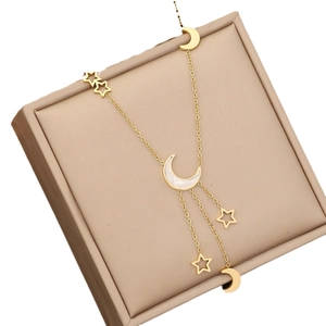 Elegant gold layered star and moon necklace displayed on a beige jewelry gift box