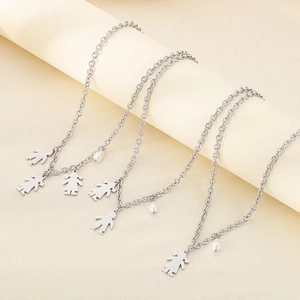 Close-up of stainless steel boy and girl silhouette pendants with pearls on silver necklaces