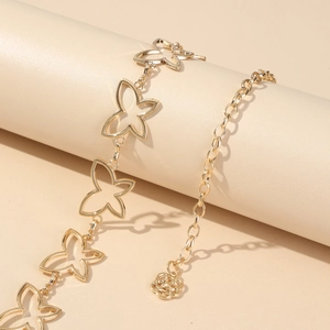 Detailed close-up of hollow butterfly links and flower pendant on a golden waist chain