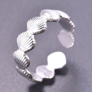 Detailed view of silver tone scallop shell relief patterns on an adjustable open ring
