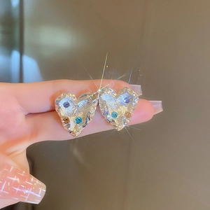 Detail of silver heart earrings featuring textured lava design and colorful rhinestones
