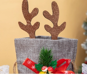 Close-up of grey burlap Christmas gift bag with glitter deer antlers and festive ribbons