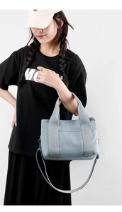Detail view of a light blue canvas tote bag with sturdy handles and a removable shoulder strap