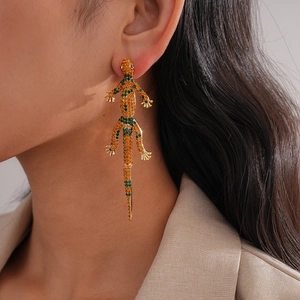 Luxury gecko drop earrings with vibrant orange and green crystals on a female model