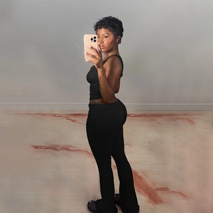 Side view of two-piece black set with cropped tank top and flared high-waist trousers