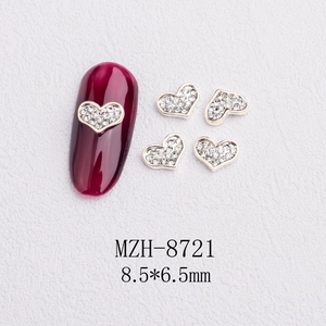 Detail of silver heart nail art charms with crystals and size 8.5x6.5mm on red nails