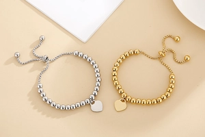 Close-up of heart charm beaded bracelets in gold and silver finish with polished spheres