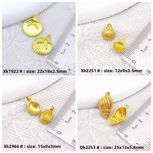 Detailed view of four golden sea shell charms with precise measurements on white cloth