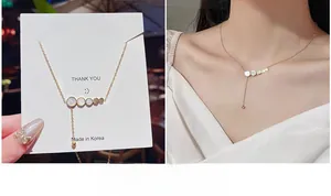 Dettaglio collana in titanio dorato con dischi di conchiglia e nappa su modella e carta