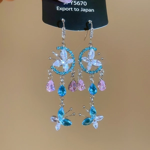 Detailed shot of butterfly moon earrings with colorful zircon tassels and floral crystals