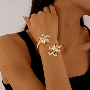 Détail d'un bracelet fleuri doré montrant la texture des pétales et le fini métallique poli