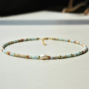 Detailed macro view of light blue and brown beads with a central freshwater pearl
