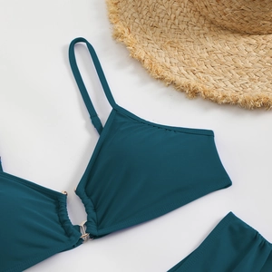 Detail of dark teal bikini top with gold metal ring and subtle ruching texture